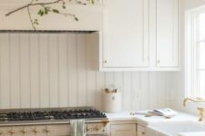 a creamy farmhouse kitchen with shaker cabinets and a matching beadboard backsplash, white stone countertops