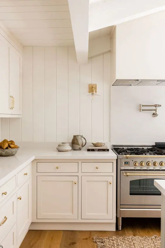 a creamy kitchen with shaker cabinets, a beadboard backsplash, stainless steel appliances and lots of natural light