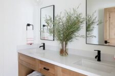 a farmhouse bathroom with a built-in timber vanity with a white stone countertop, black fixtures and mirrors in black frames