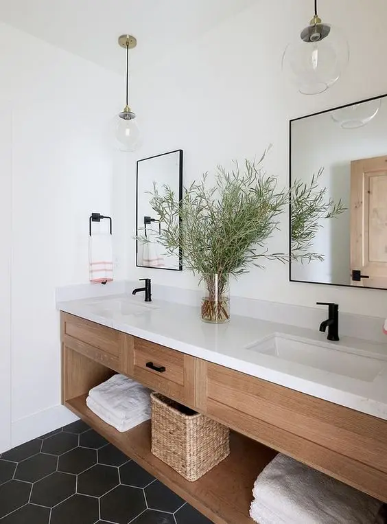 a farmhouse bathroom with a built-in timber vanity with a white stone countertop, black fixtures and mirrors in black frames