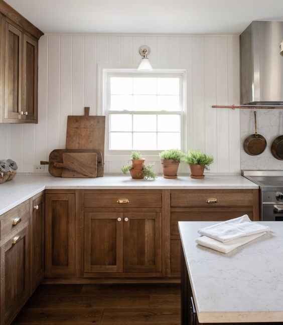 a farmhouse kitchen with shaker cabinets, a white beadboard backsplash and white countertops plus copper touches