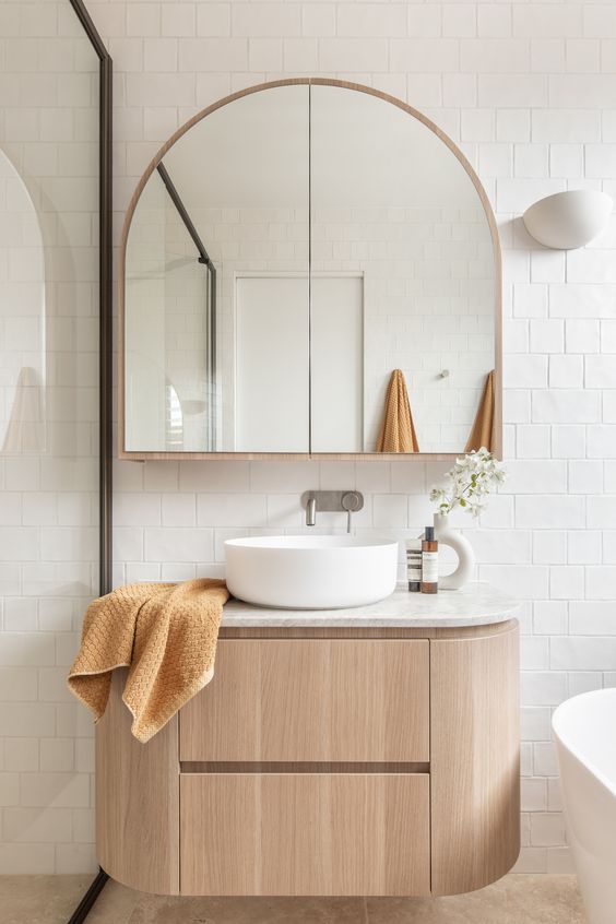 a floating curved timber vanity, an arched mirror cabinet, a white sink are all the rage considering current home decor trends