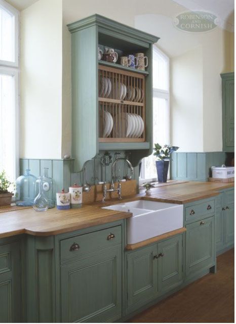 a green vintage kitchen with shaker cabinets, an open dish storage unit, butcherblock countertops and vintage fixtures