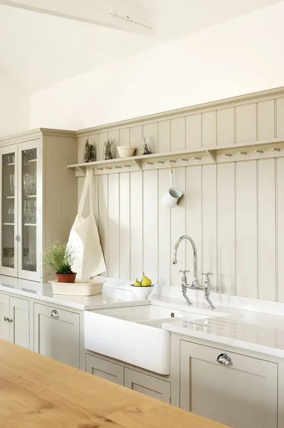 a greige kitchen with shaker cabinetry, a matching beadboard backsplash, white appliances and potted greenery