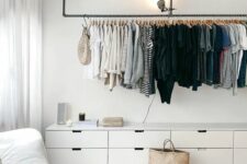 a lovely makeshift closet with a long railing for hanging clothes and a long white dresser to store smaller things