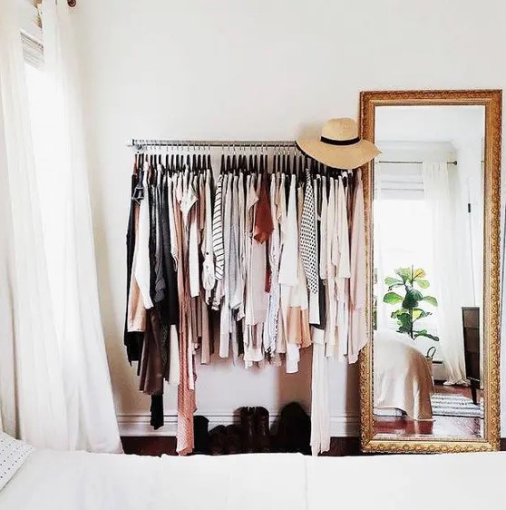 a metal rack for clothes and shelves plus a floor mirror in a heavy gilded frame are a great combo for a makeshift closet