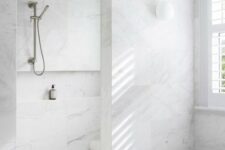 a minimalist bathroom clad with white marble tiles, a shower space and a bathtub is a chic space