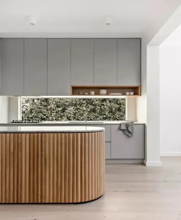a minimalist grey kitchen with a window backsplash and a curved fluted kitchen island with a terrazzo countertop looks ultimate