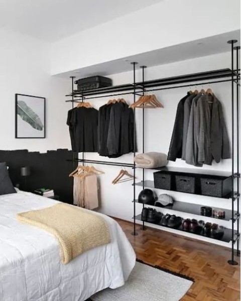 a minimalist makeshift closet made of black pipes, with clothes racks and hangers, boxes and some hat and shoe shelves