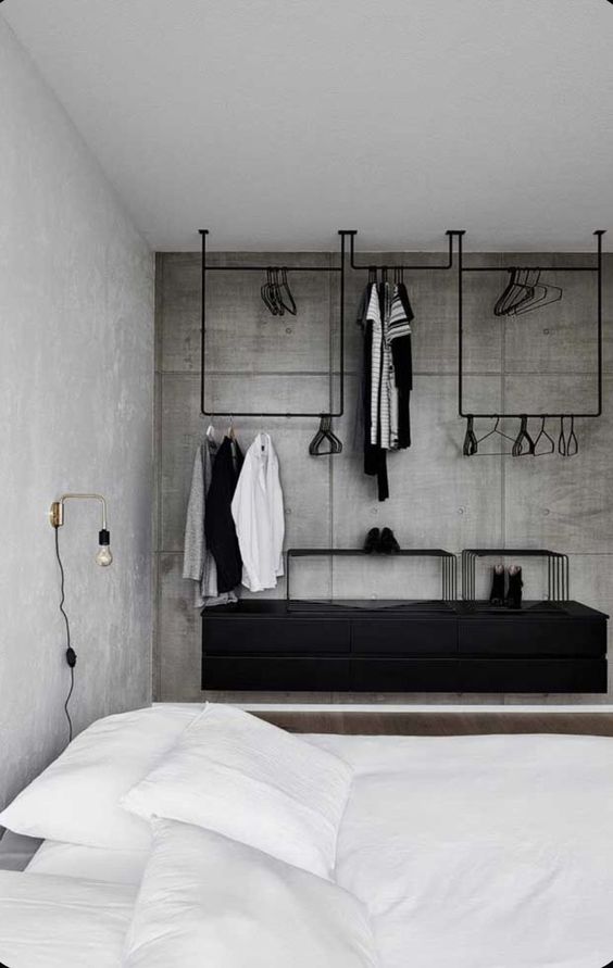 a minimalist makeshift closet with black metal railings and racks, a black floating dresser is a stylish addition to the bedroom