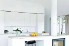 a minimalist white kitchen is made more interesting with a kitchen island with an integrated hearth and firewood storage