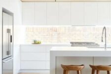 a minimalist white kitchen with a wooden ceiling, stools and an eye-catchy backsplash