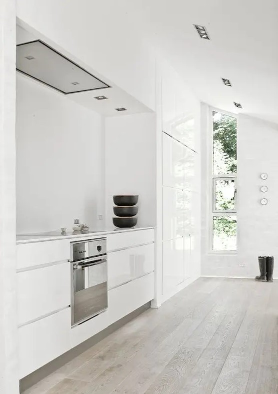 a minimalist white space with sleek cabinets and a vertical window to bring much light in looks clean and fresh
