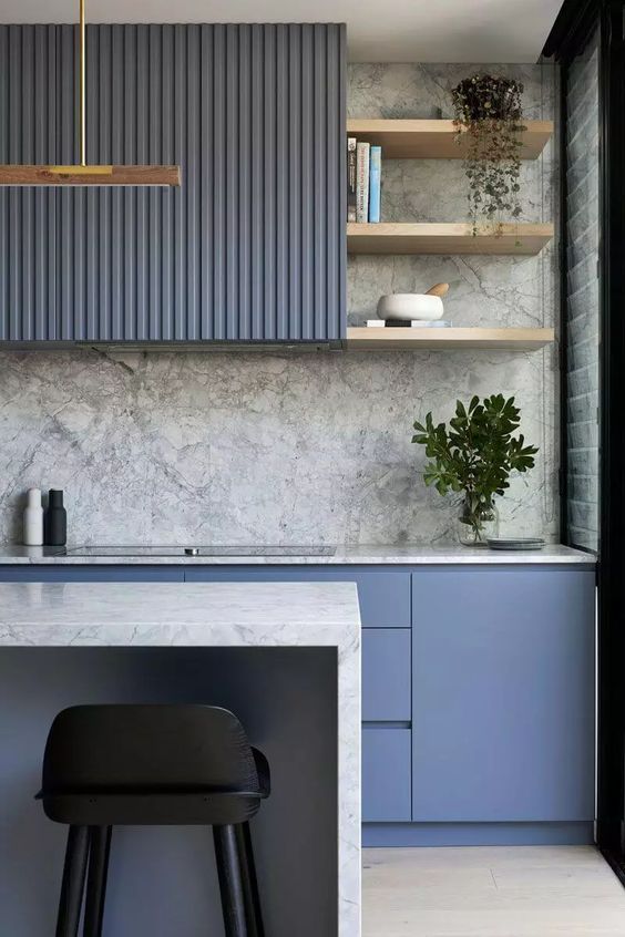 a minimalist yet bold kitchen with periwinkle fluted and sleek cabinets, a grey marble backsplash and countertops