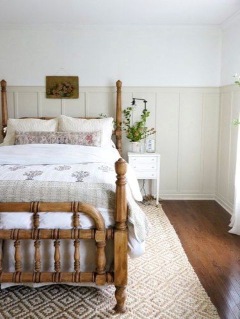 a modern farmhouse neutral bedroom clad with neutral beadboard, with a vintage stained bed and printed bedding