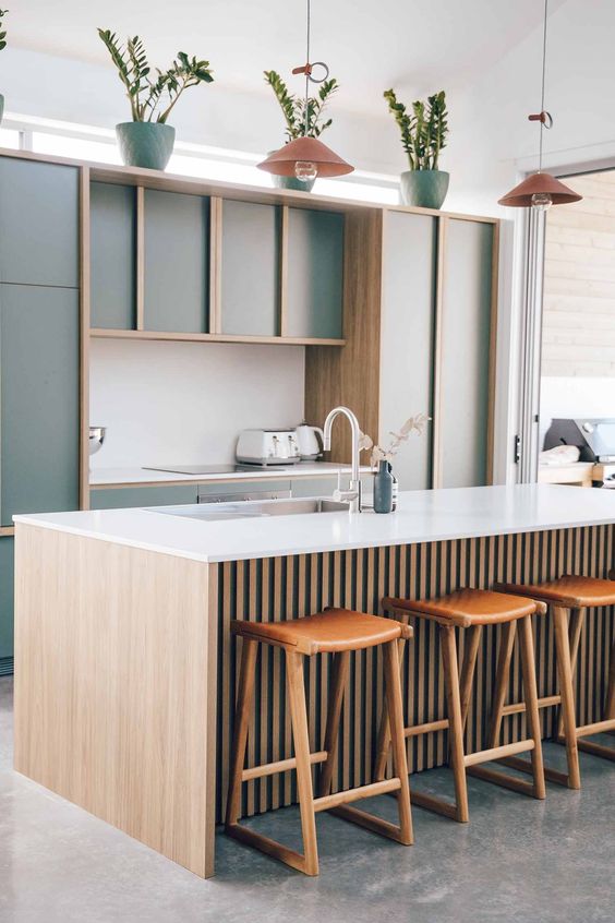 a modern kitchen with green plywood cabinetry, a stained fluted kitchen island, white countertops and green and coral touches