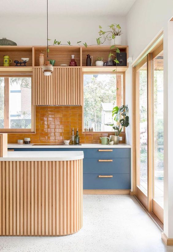 a modern kitchen with slate blue cabinets, a stained fluted one plus a stained fluted kitchen island and an orange tile backsplash
