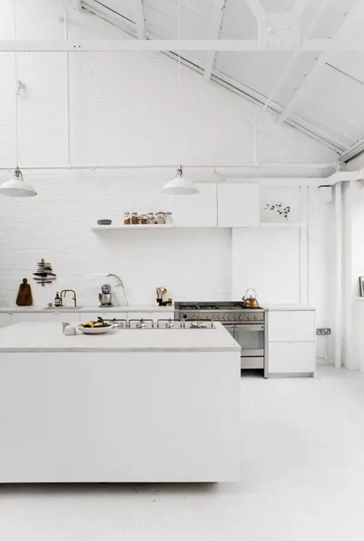 a modern whitewashed space with whitewashed brick walls and a sloped ceiling and lamps