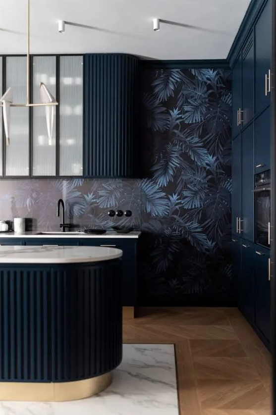 a moody and elegant kitchen with midnight blue curved and fluted cabinets and a matching kitchen island, dark wallpaper on the walls and black fixtures