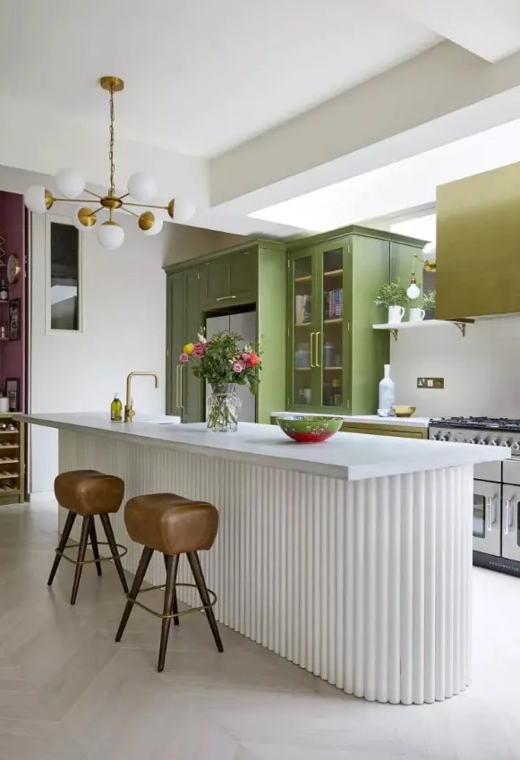 a mustard and green kitchen with usual and glass door cabinets, a matching hood, a white fluted kitchen island with a stone countertop