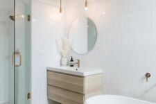 a neutral bathroom with white tiles and terrazzo, a shower and an oval tub, a floating timber vanity and a round mirror