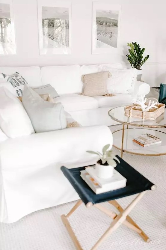 a neutral living room with a white Ektorp sofa, a navy stool, a round tiered coffee table and a gallery wall with family vacation pics
