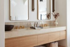 a neutral space with a large built-in timber vanity with a stone countertop, a couple of mirrors in brass frames