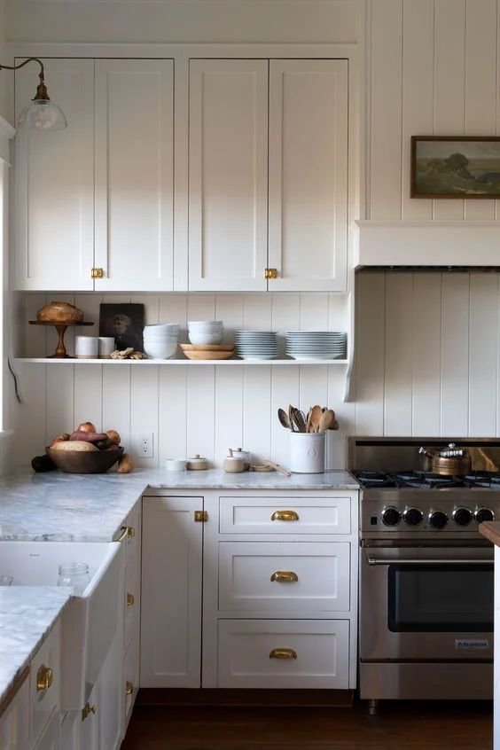 a neutral vintage kitchen with shaker cabinets, a matching beadboard backsplash, a grey stone countertop and some art