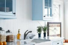 a pastel blue kitchen with a white beadboard backsplash, white stone countertops and a white sink is airy and cool