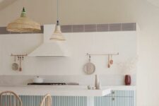 a serene coastal kitchen with light blue ribbed cabinets and a kitchen island, white countertops and woven pendant lamps