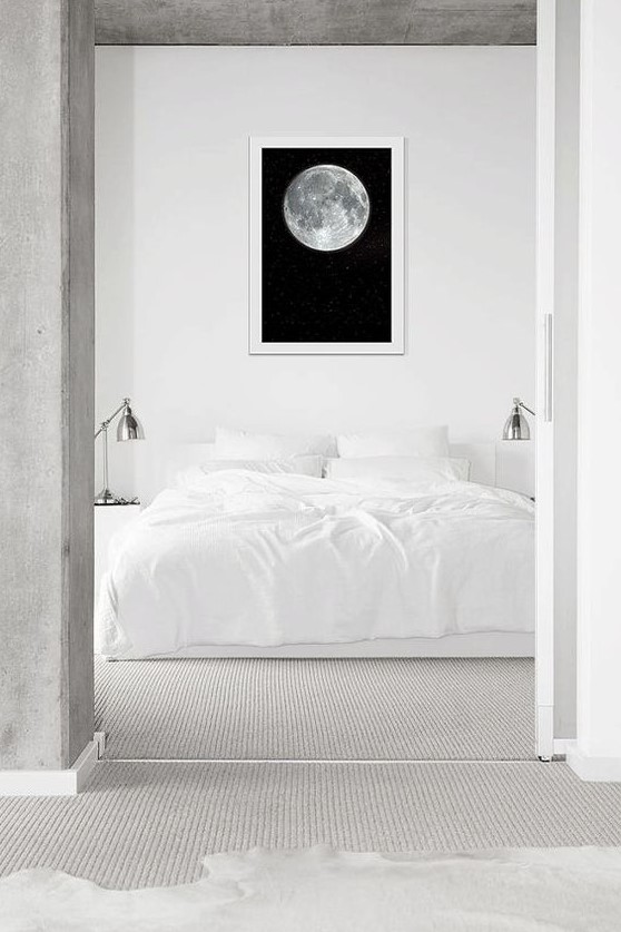 a serene minimal bedroom in white, with a statement artwork, metallic sconces and neutral textiles is very welcoming