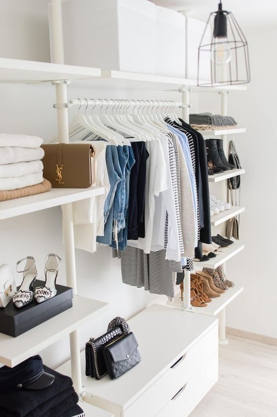 a small and stylish makeshift closet in white, with shelves, a holder for clothes hangers and a dresser for smaller stuff