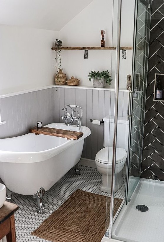 a small cute bathroom with grey beadboard, a black tile shower space, some wood tiles and potted greenery