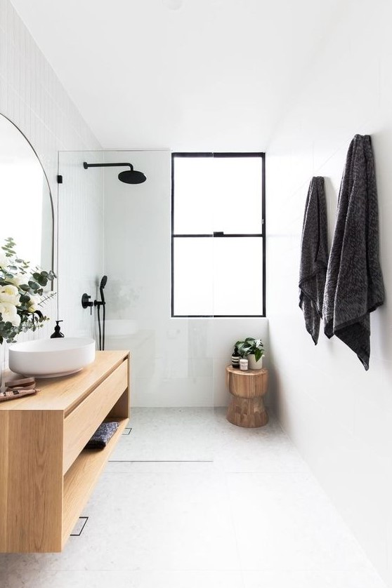 a small minimalist bathroom with white tiles, a floating vanity, a shower space, a stump table and black fixtures