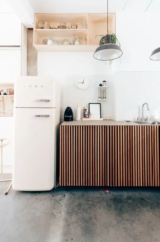 a small relaxed kitchen with ribbed cabinets, a niche-like storage unit as an upper cabinet and a Smeg fridge