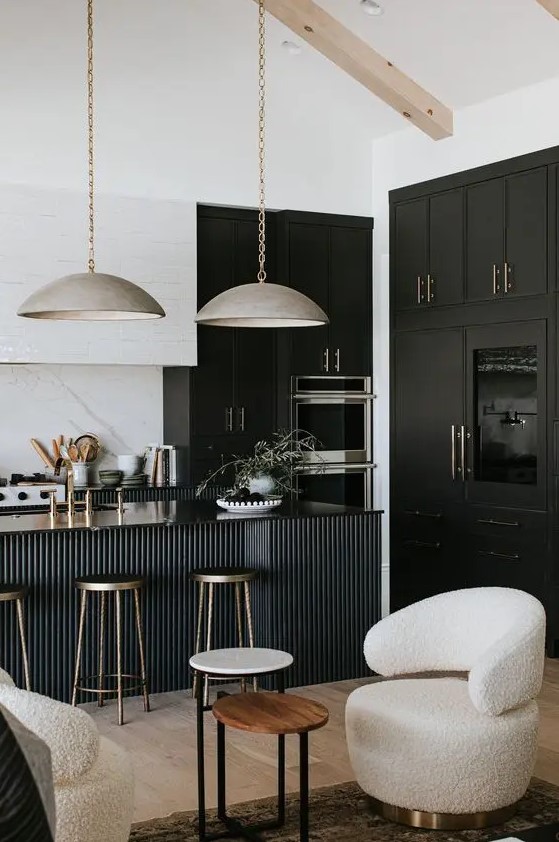 a sophisticated black and white kitchen with black and white cabinets, a black fluted kitchen island and gorgeous metal lamps hanging on chain