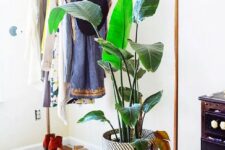 a stylish makeshift closet with a metal and stained wood rack for clothes and shoes and a dark-stained dresser plus a potted plant