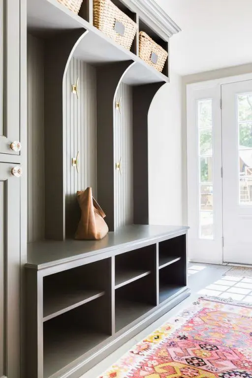 a stylish mudroom with a grey beadboard storage unit, baskets and a bold rug looks nice and cool