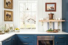 a stylish navy kitchen with shaker cabinets, a white shiplap backsplash, vintage artwork and wooden beams