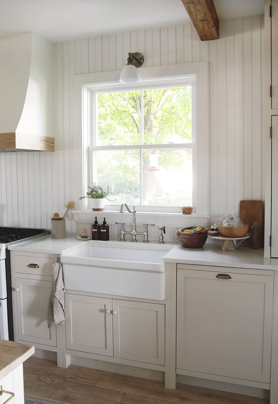 a tan kitchen with shaker cabinets, a white beadboard backsplash, touches of stained wood for a cozy feel