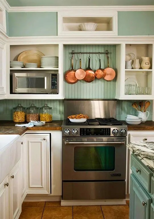 a vintage cream kitchen with shaker cabinets, built-in box shelves, a green beadboard backsplash and a green kitchen island