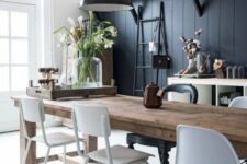 a vintage dining room with a black beadboard wall, black pendant lamps, a wooden table and white chairs looks chic