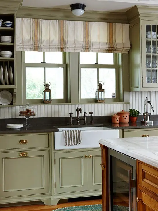 a vintage green kitchen with shaker cabinets, open and glass ones, a white beadboard backsplash and black countertops