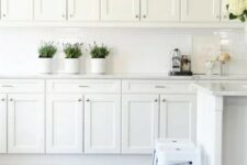 a vintage white kitchen with a white tile backsplash, stools and much storage space