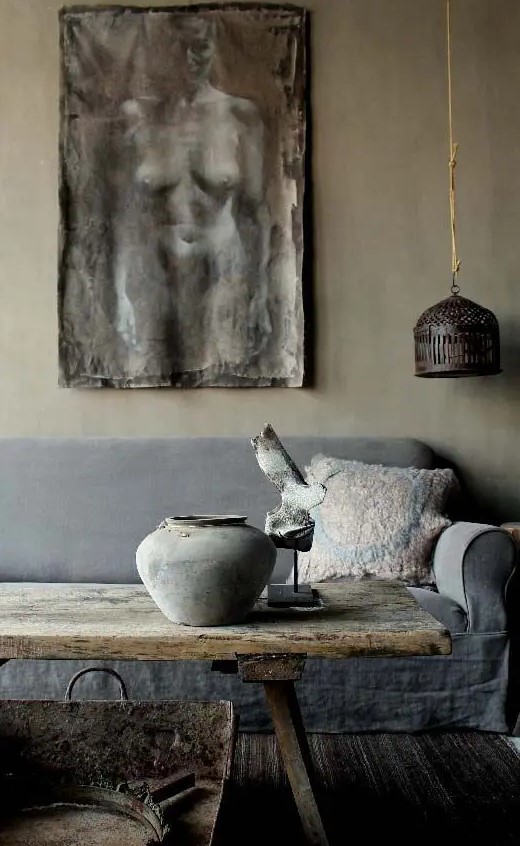 a wabi sabi living room with a pendant lamp, an artwork, a rough wooden coffee table and a metal bathtub