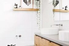 a welcoming Nordic bathroom with white hex and large scale tiles, a double vanity, round sinks and some art and greenery
