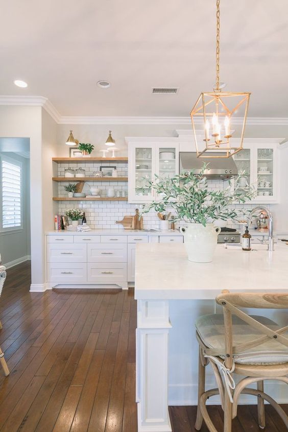 a welcoming white farmhouse kitchen with shaker style cabinets, a white subway tile backsplash, open shelves, pendant lamps