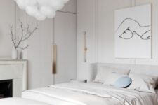 a white bedroom with paneling on the walls, a fireplace, an upholstered bed and a bench, a bubble chandelier