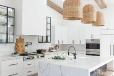 a white contemporary kitchen with white cabinets and black handles, a large hood, a kitchen island with a seating zone and woven pendant lamps