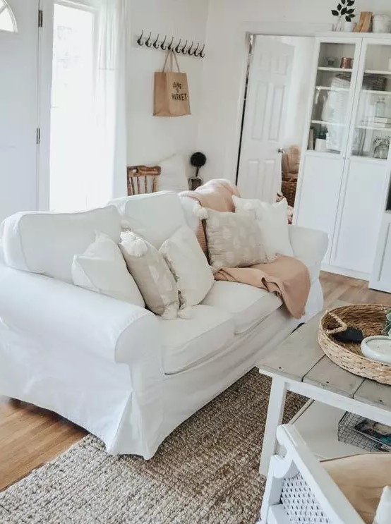 a white farmhouse living room with an Ektorp sofa, white glass cabinets, a low wooden table and chairs is welcoming